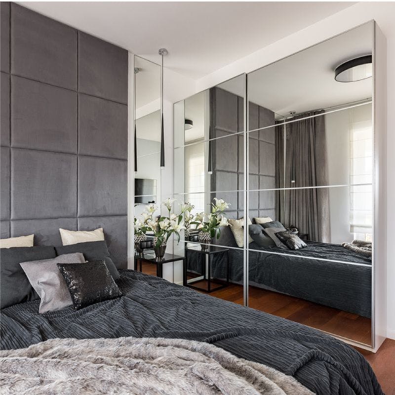 Spacious bedroom with a big mirror and cozy bed