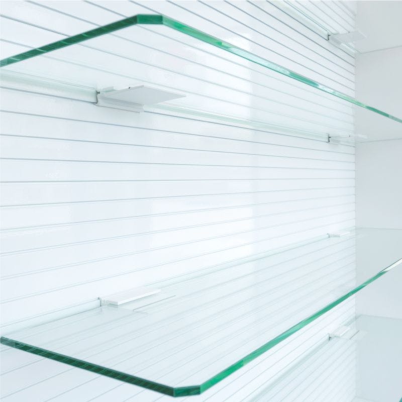 Glass shelves displaying merchandise in an office with pristine white walls