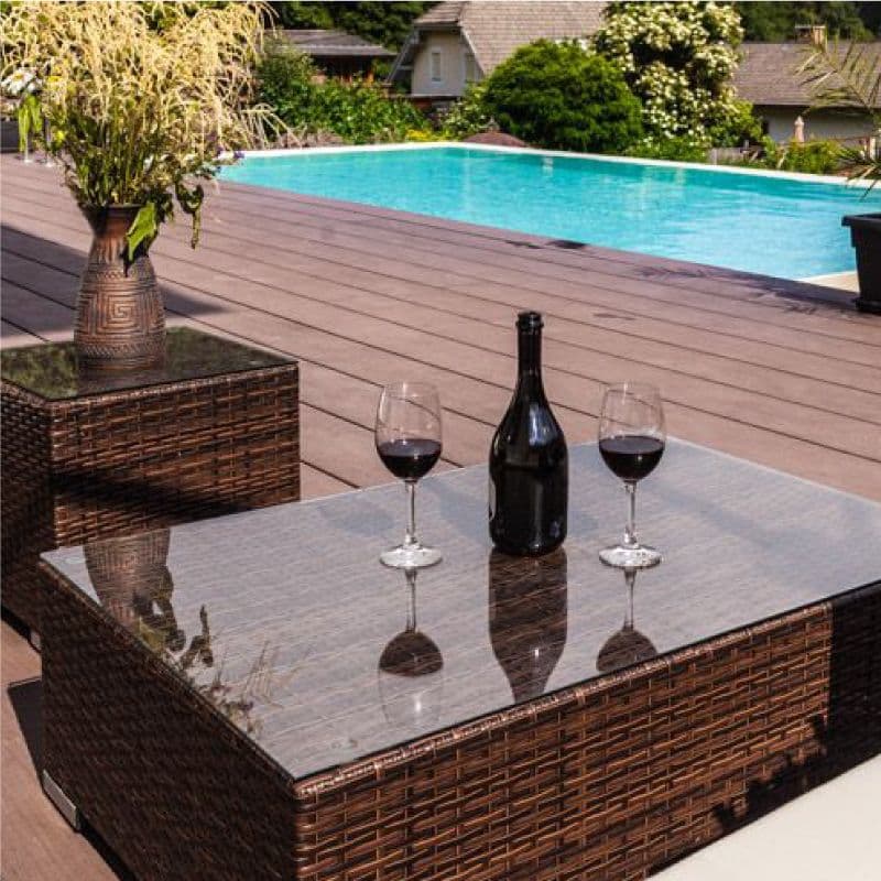 Luxury outdoor setting featuring a glass-topped table, wine glasses, and a pool, showcasing custom glass solutions for table tops and tempered glass.