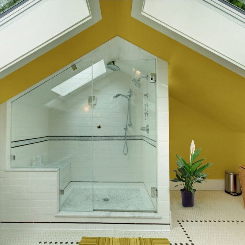 A well-lit bathroom featuring a shower and a skylight with angled ceiling