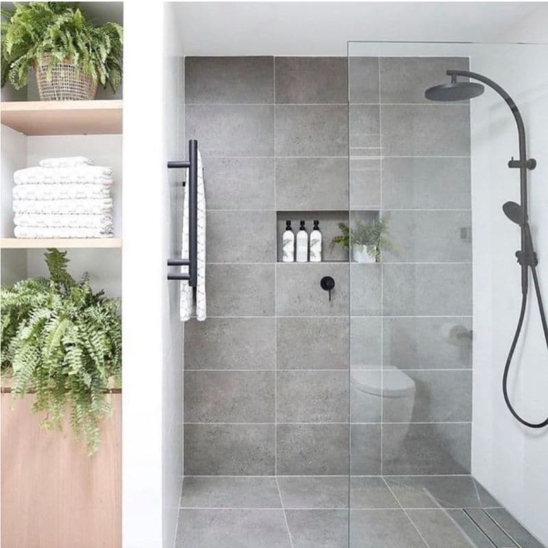 Modern bathroom featuring a frameless glass shower door, sleek tile design, and stylish natural elements, showcasing custom glass solutions for a contemporary aesthetic.