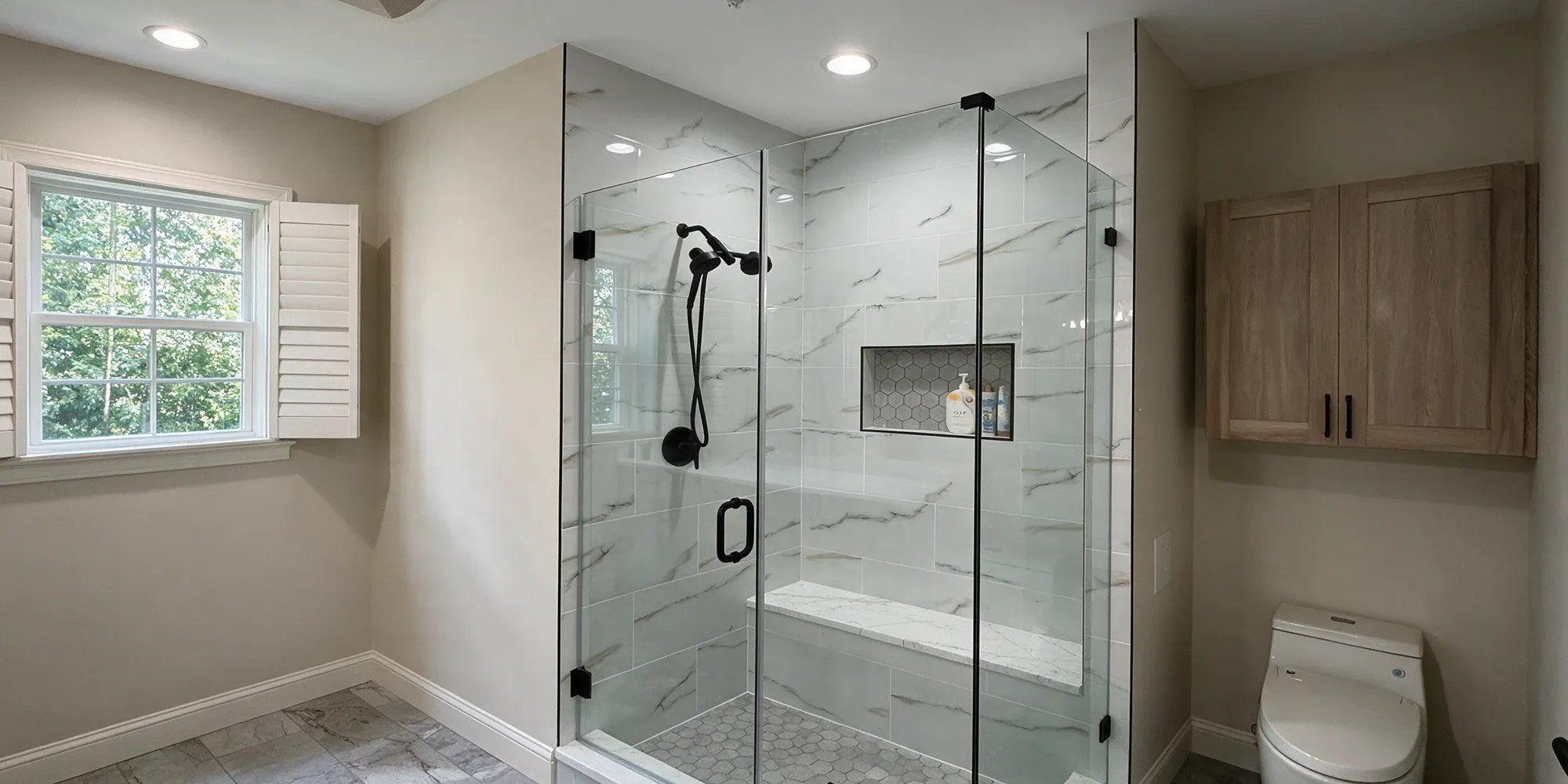 Finished frameless shower enclosure with a hinged door and matte black hardware in a Fairfax, VA bathroom