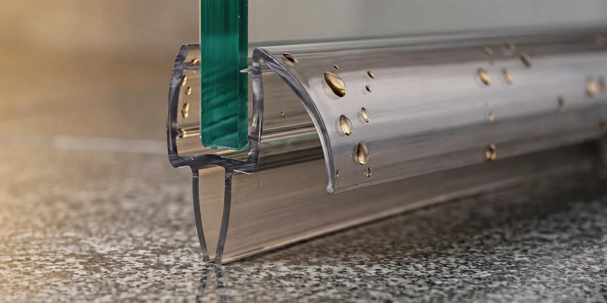 U-channel shower door sweep gripping the bottom edge of the glass with its flexible fin meeting the threshold