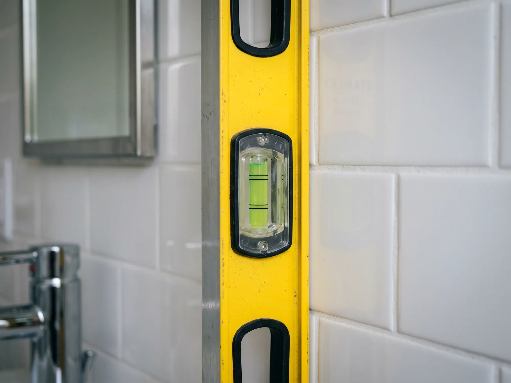 An installer checking an out-of-plumb shower wall so the custom panel is fabricated to fit