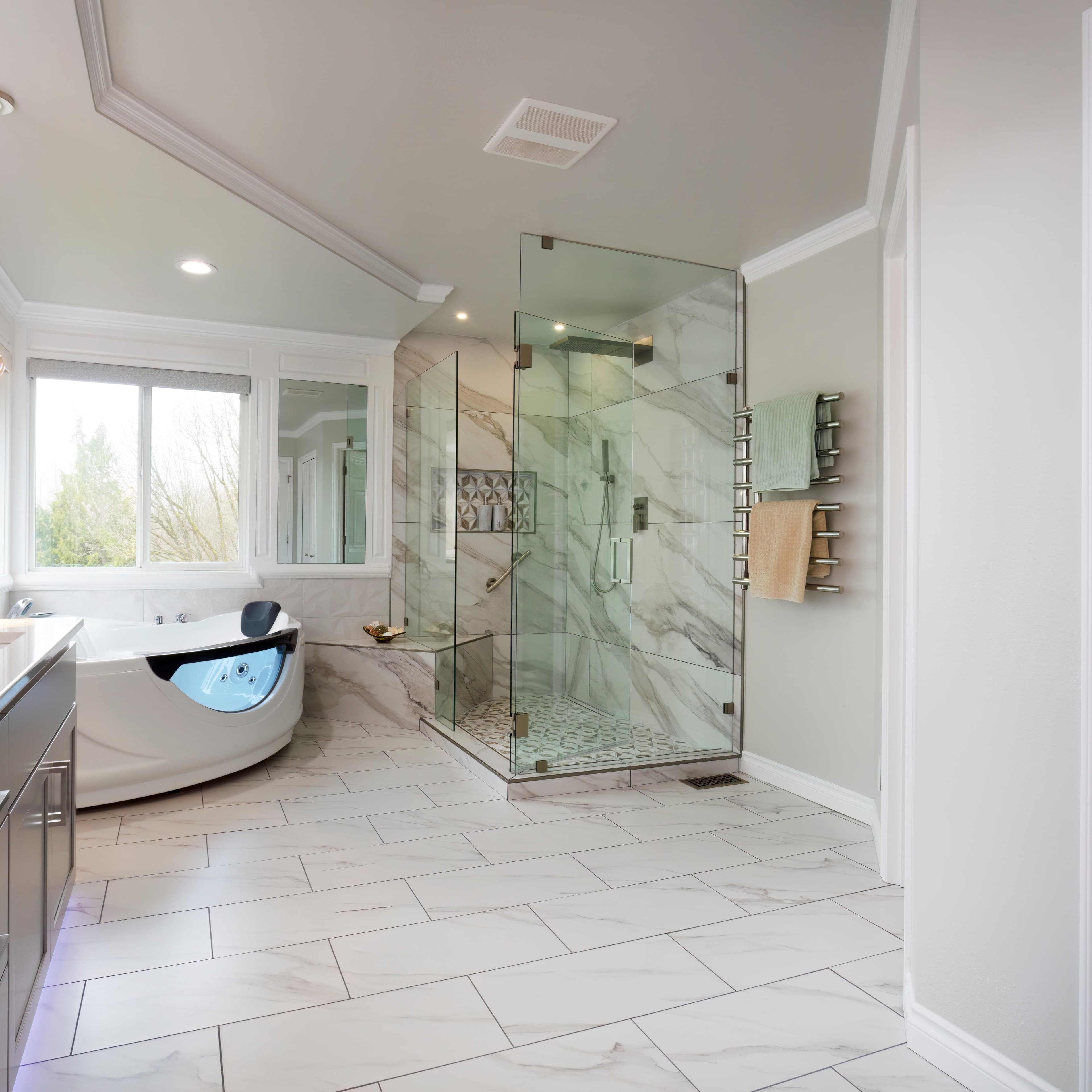 Luxurious bathroom featuring a frameless glass shower enclosure with marble walls, built-in bench, and a soaking bathtub with a scenic window view.