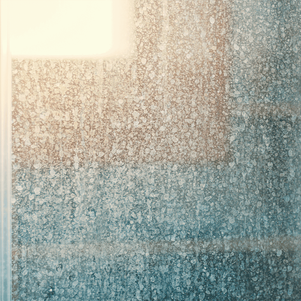 Close-up of a textured glass surface, showcasing water droplets, ideal for shower doors, custom glass, and tempered glass applications.