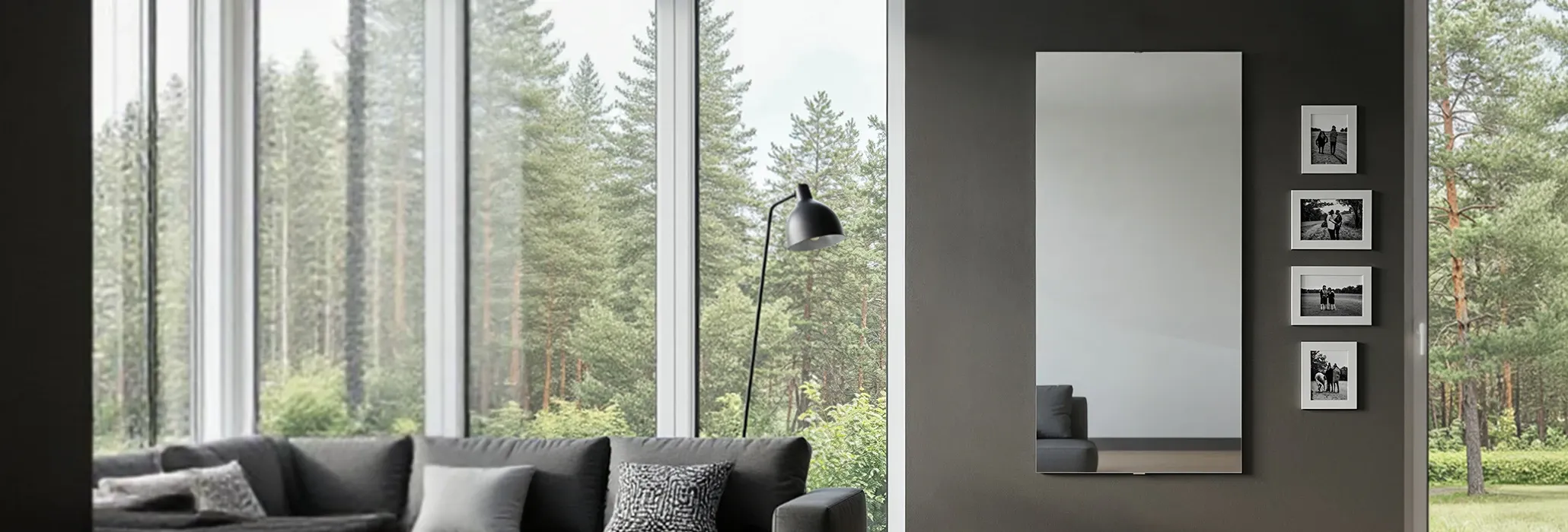 write alt text, make it short, concise write alt text, make it short, concise Gemini response A modern living room features a large vertical mirror on a dark gray wall, reflecting a part of the gray sofa and ottoman. To the right of the mirror, four framed black and white photos are hung vertically. A large window on the left side of the room provides a view of trees and nature, with a tall, angled floor lamp nearby.