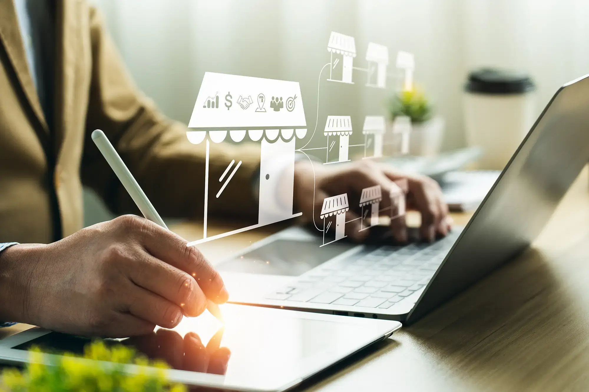 Businessman using tablet and laptop to manage a digital franchise network with interconnected retail store icons.