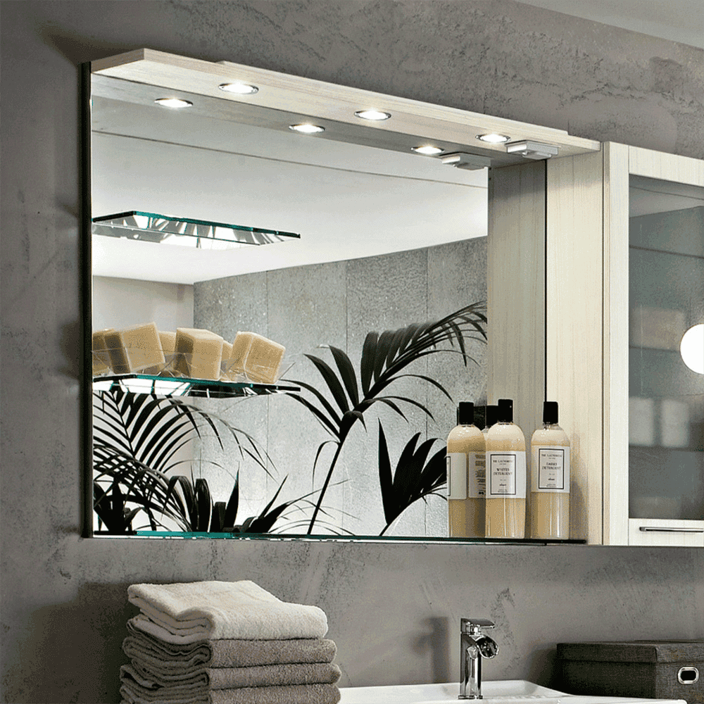Custom glass mirror with beveled edges and integrated lighting, showcasing a sleek bathroom setup with shower doors, towels, and tempered glass shelves.