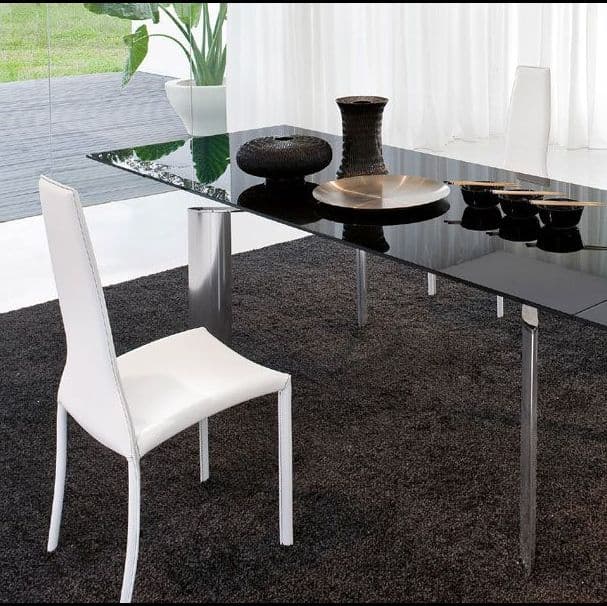 Modern dining area featuring a sleek glass table top with a black finish, accented by decorative items, a white chair, and natural lighting, highlighting the elegance of custom glass design.