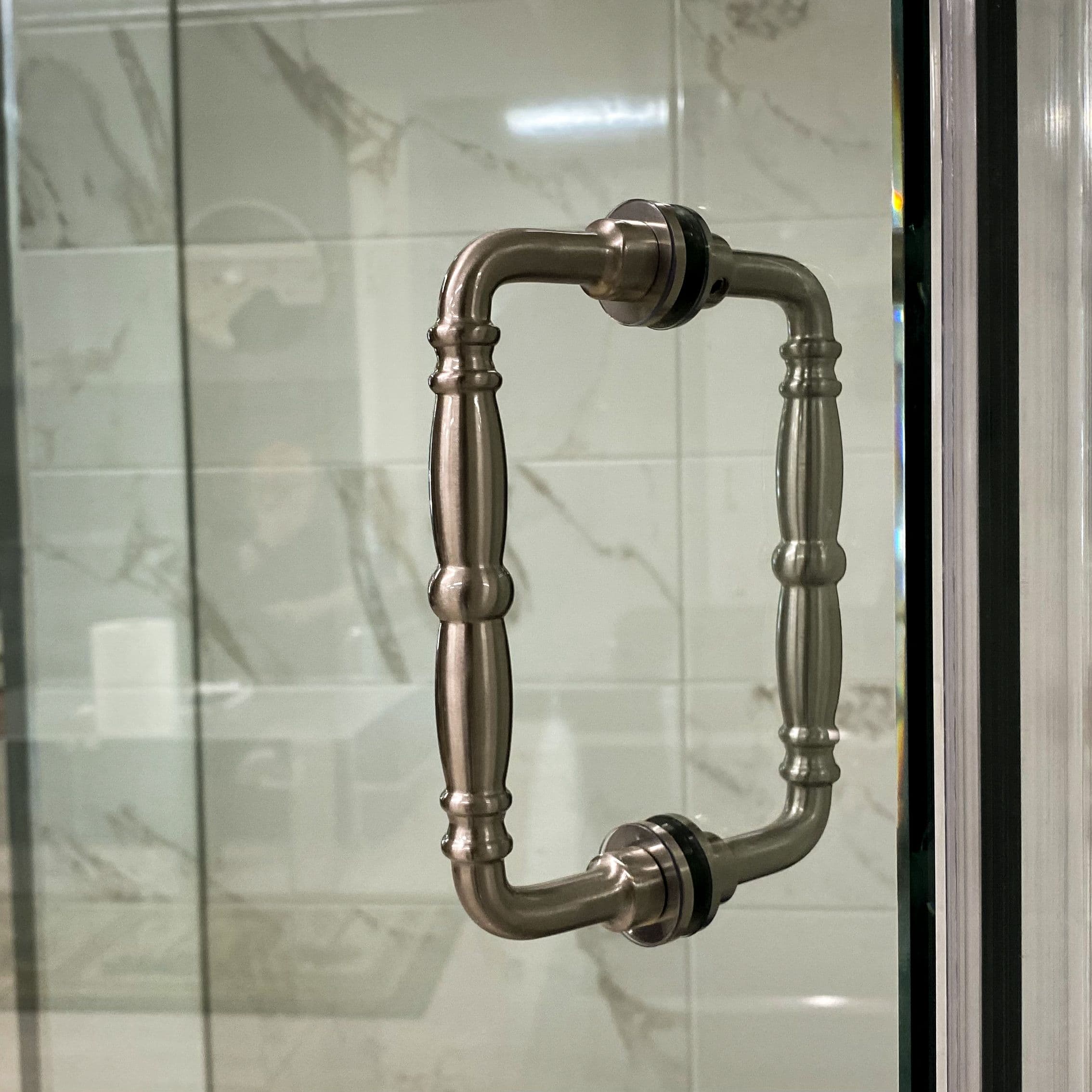 Close-up of a decorative shower door handle on a custom glass shower enclosure, highlighting the craftsmanship of tempered glass and the sleek design suitable for modern bathroom aesthetics.