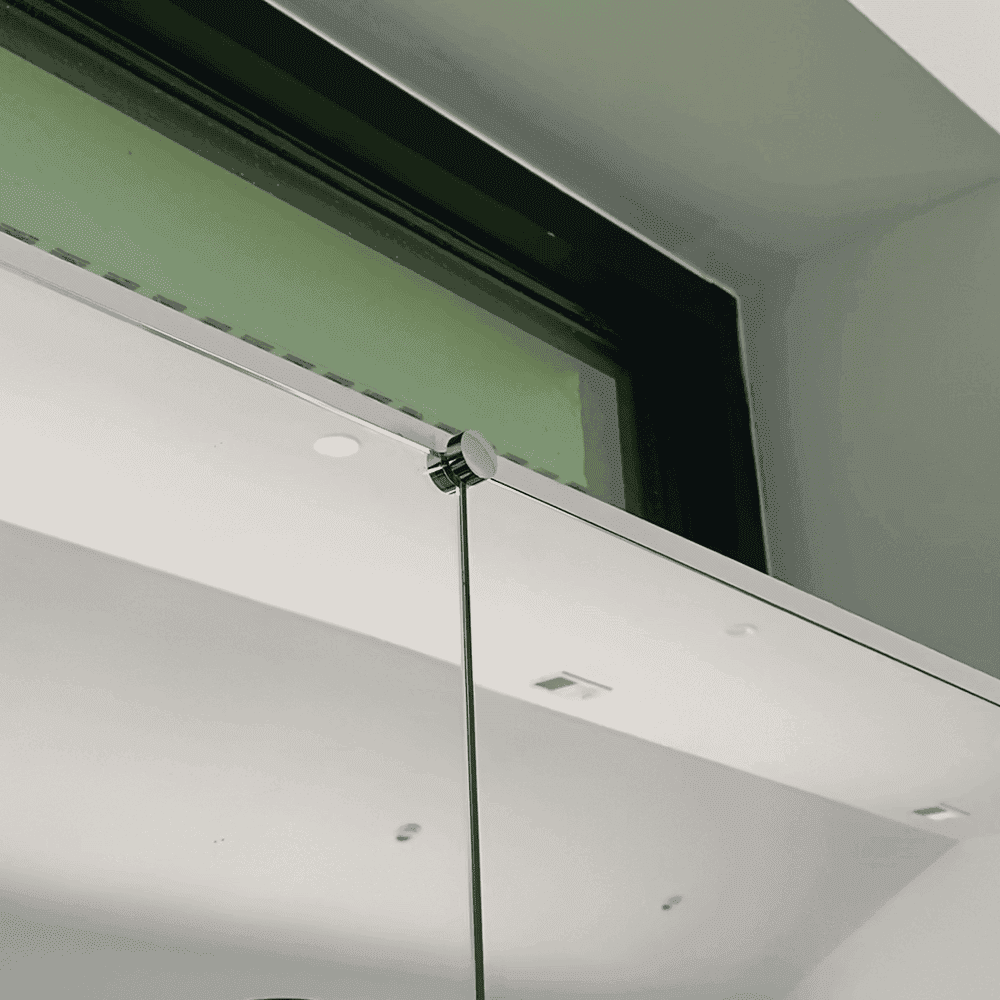 Modern custom glass shower door installation featuring a sleek design with tempered glass and a polished bevel edge, showcasing reflective mirrors and ambient lighting.