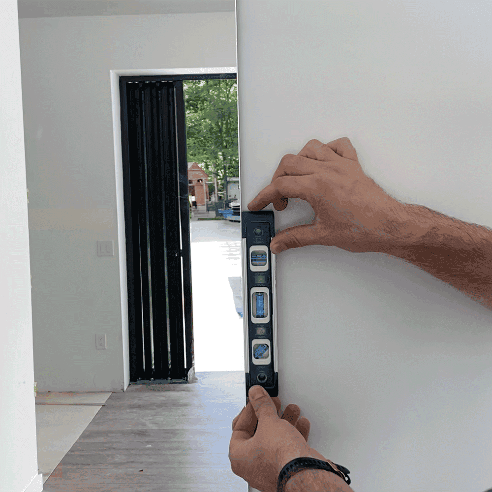 A person using a level tool to ensure proper placement of a custom mirror installation, showcasing quality craftsmanship in custom glass solutions, including shower doors and beveled glass edges.
