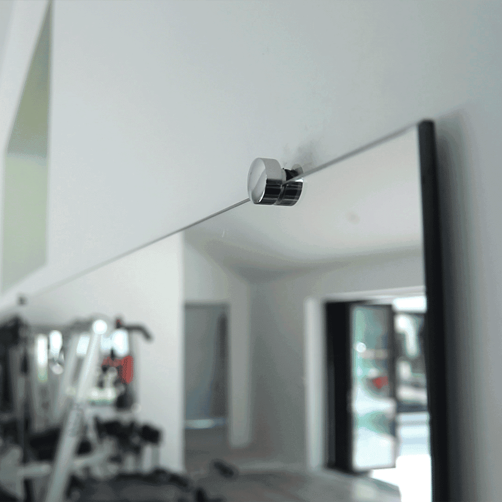 Close-up of a modern mirror held by a sleek mounting hardware, showcasing custom glass design suitable for shower doors, table tops, and beveled glass edges.