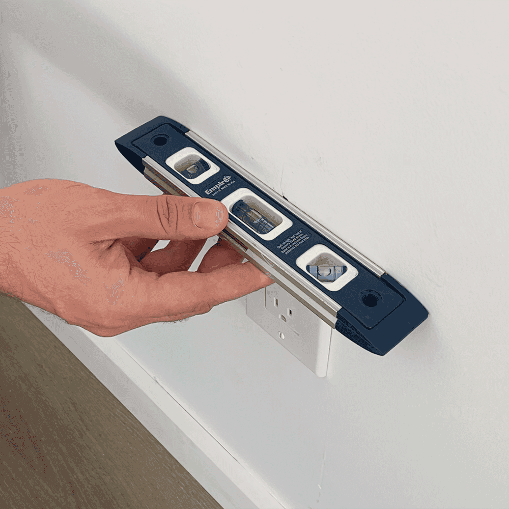 Person using a level tool to ensure accurate installation of custom glass features like shower doors, table tops, and mirrors with beveled glass edges.