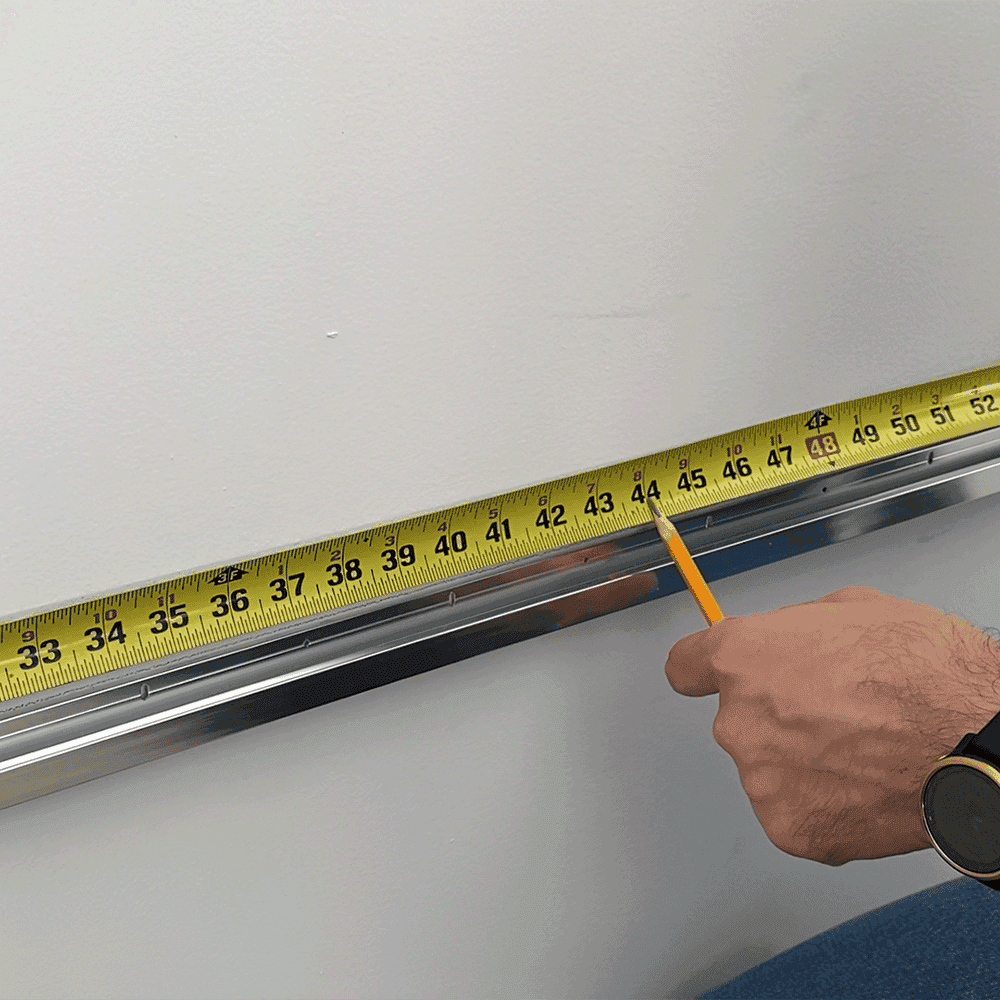 Measuring for custom glass installation with a tape measure and pencil, focusing on precision for shower doors, table tops, and mirrors.