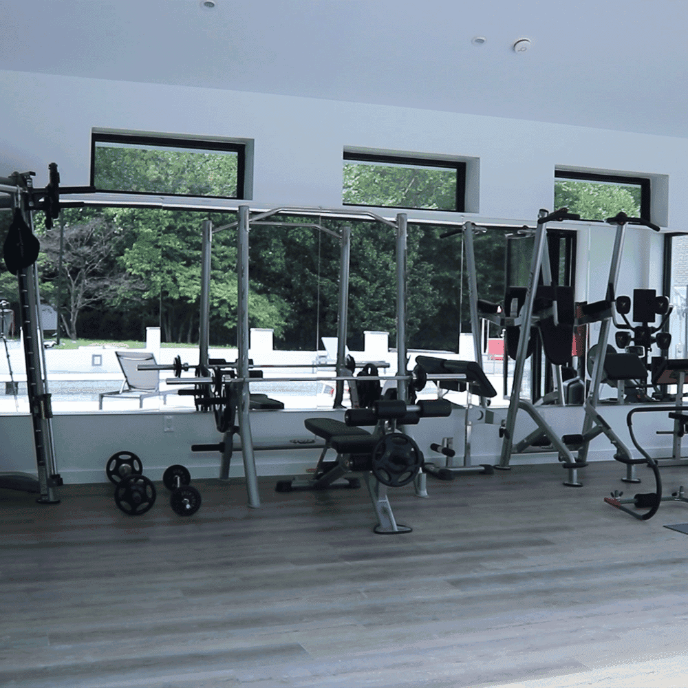 Custom glass mirrors in a modern gym setting with workout equipment and natural light