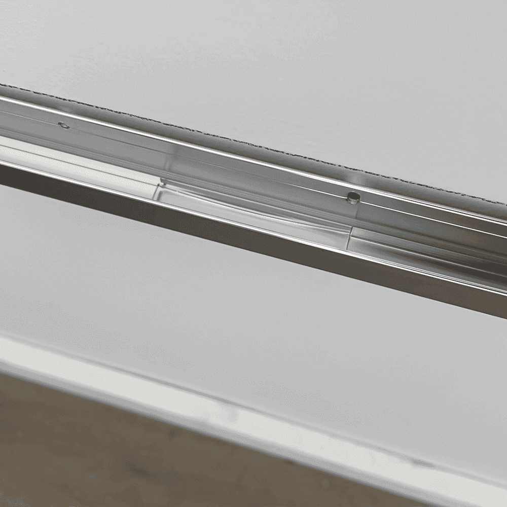 Close-up view of a sleek, modern shower door track, highlighting custom glass solutions, including tempered glass and options for beveled glass edges.