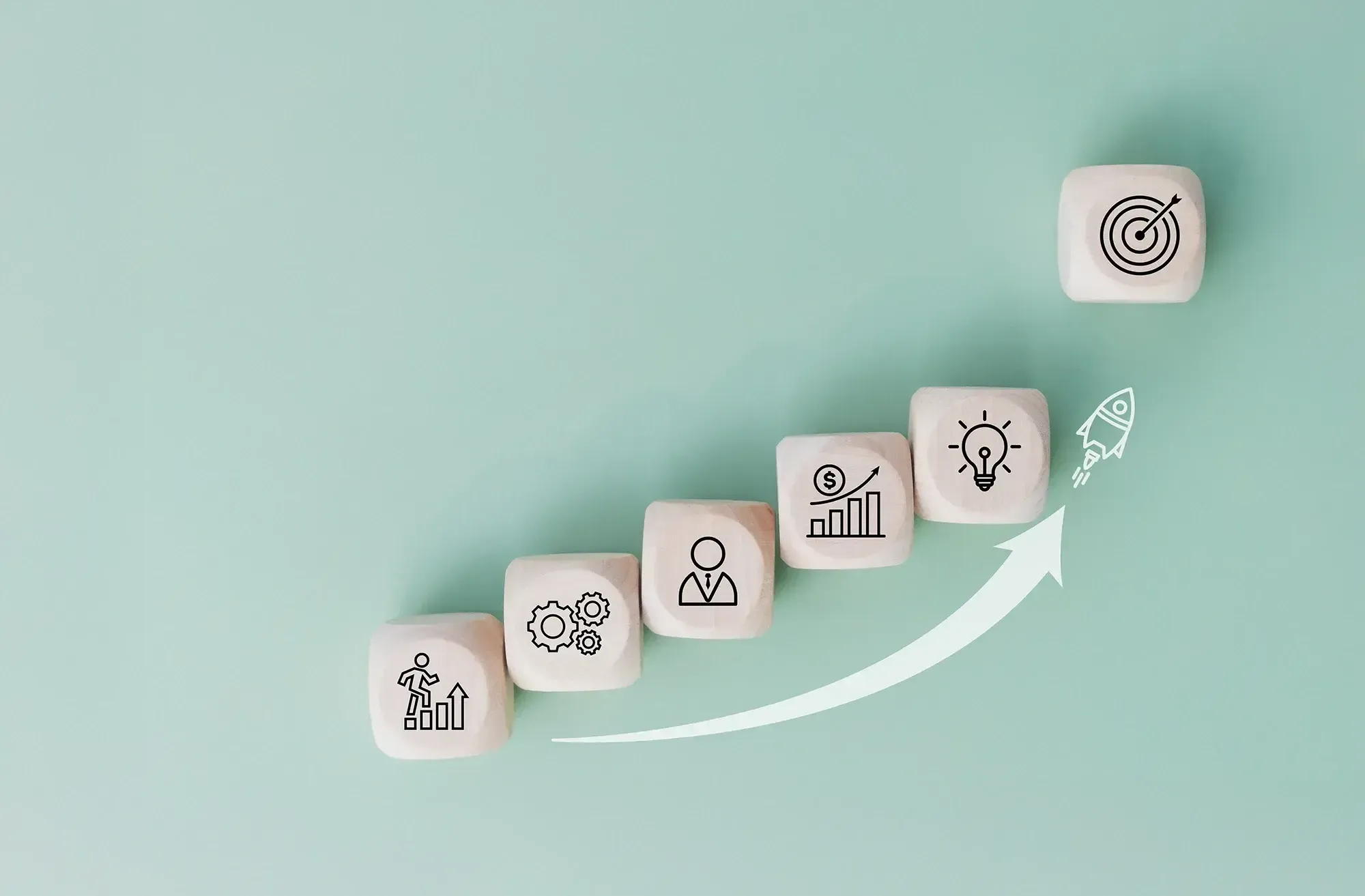 Steps to business success shown as wooden blocks with icons for growth, leadership, finance, innovation, and goals.