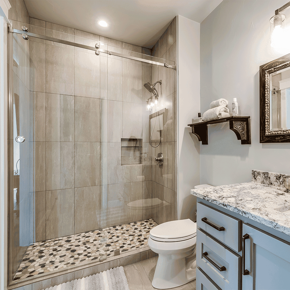 Custom glass shower doors in modern bathroom design featuring elegant stone tiles and a chic granite countertop, complemented by a beveled glass edge mirror.