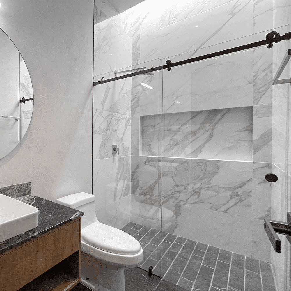 Contemporary bathroom featuring custom glass shower doors, a round mirror, marble walls, and stylish fixtures, showcasing tempered glass and sleek design elements.