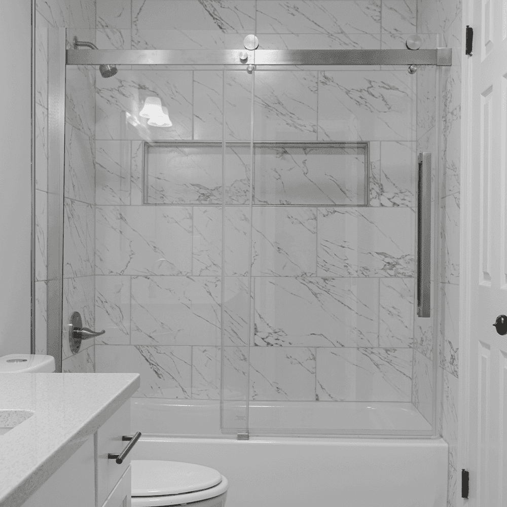 Modern bathroom featuring a custom glass shower door with a sleek design, showcasing tempered glass and a stylish marble tile backdrop.