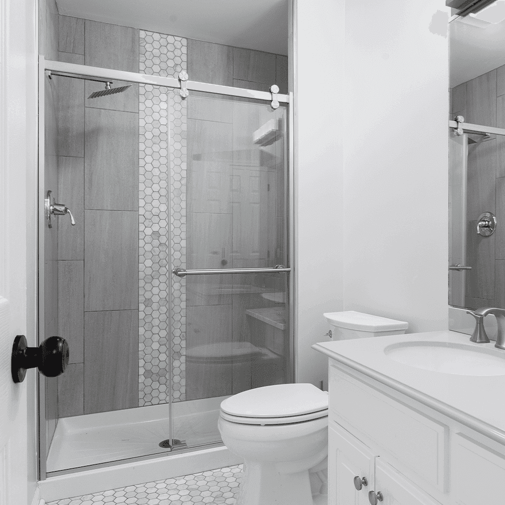 Modern bathroom featuring custom shower doors, sleek fixtures, and a stylish mirror, showcasing high-quality tempered glass and elegant design elements.