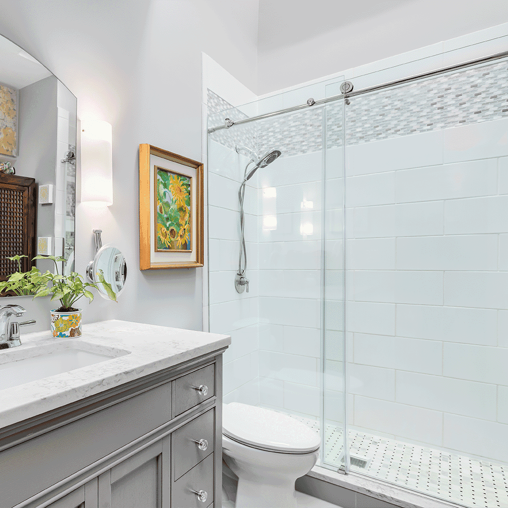 Modern bathroom featuring custom shower doors, sleek marble table top, and a stylish mirror, emphasizing high-quality tempered glass and beveled glass edge design elements.