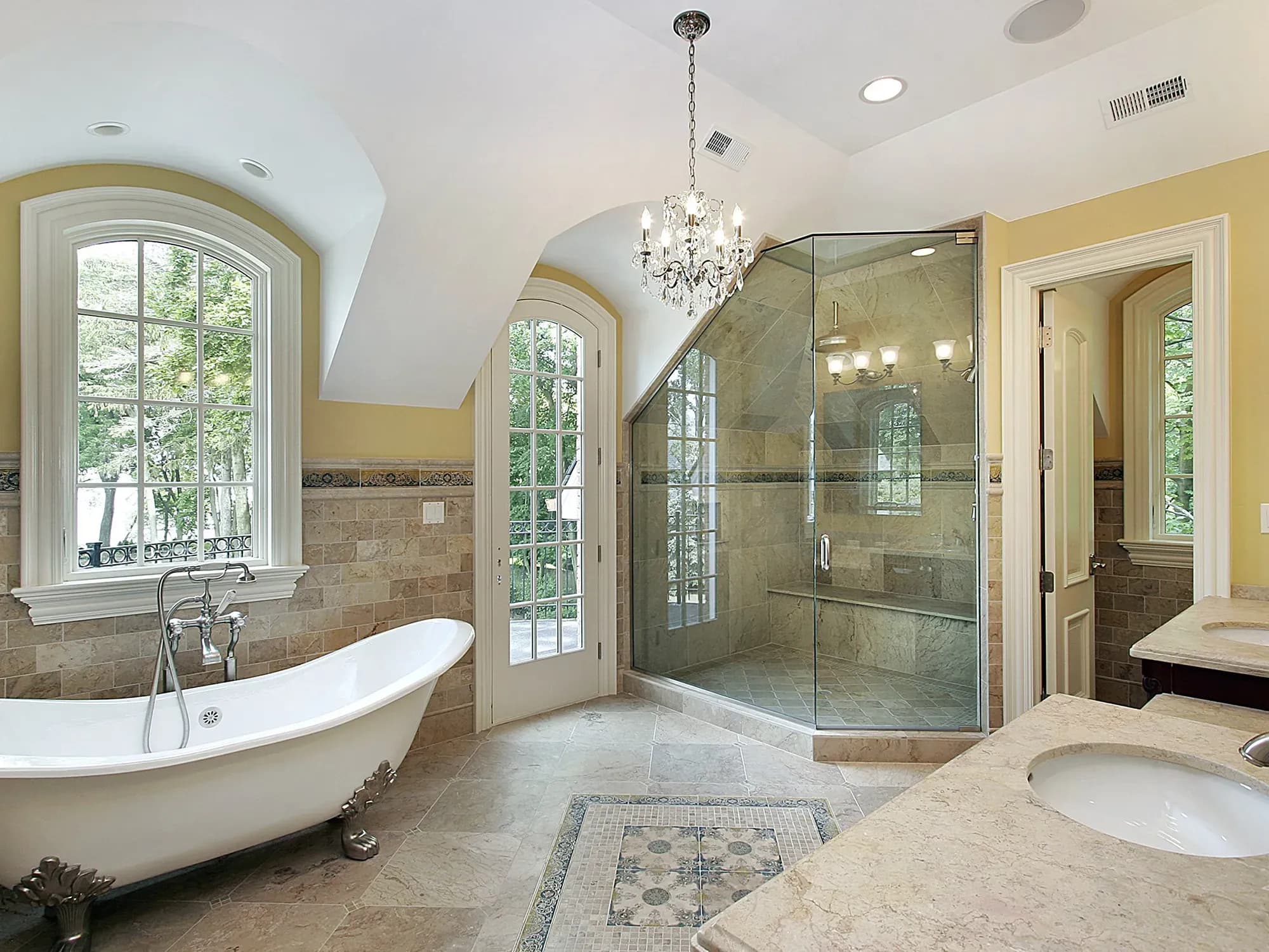 An elegant bathroom with a custom frameless glass shower enclosure fitted under an arched ceiling