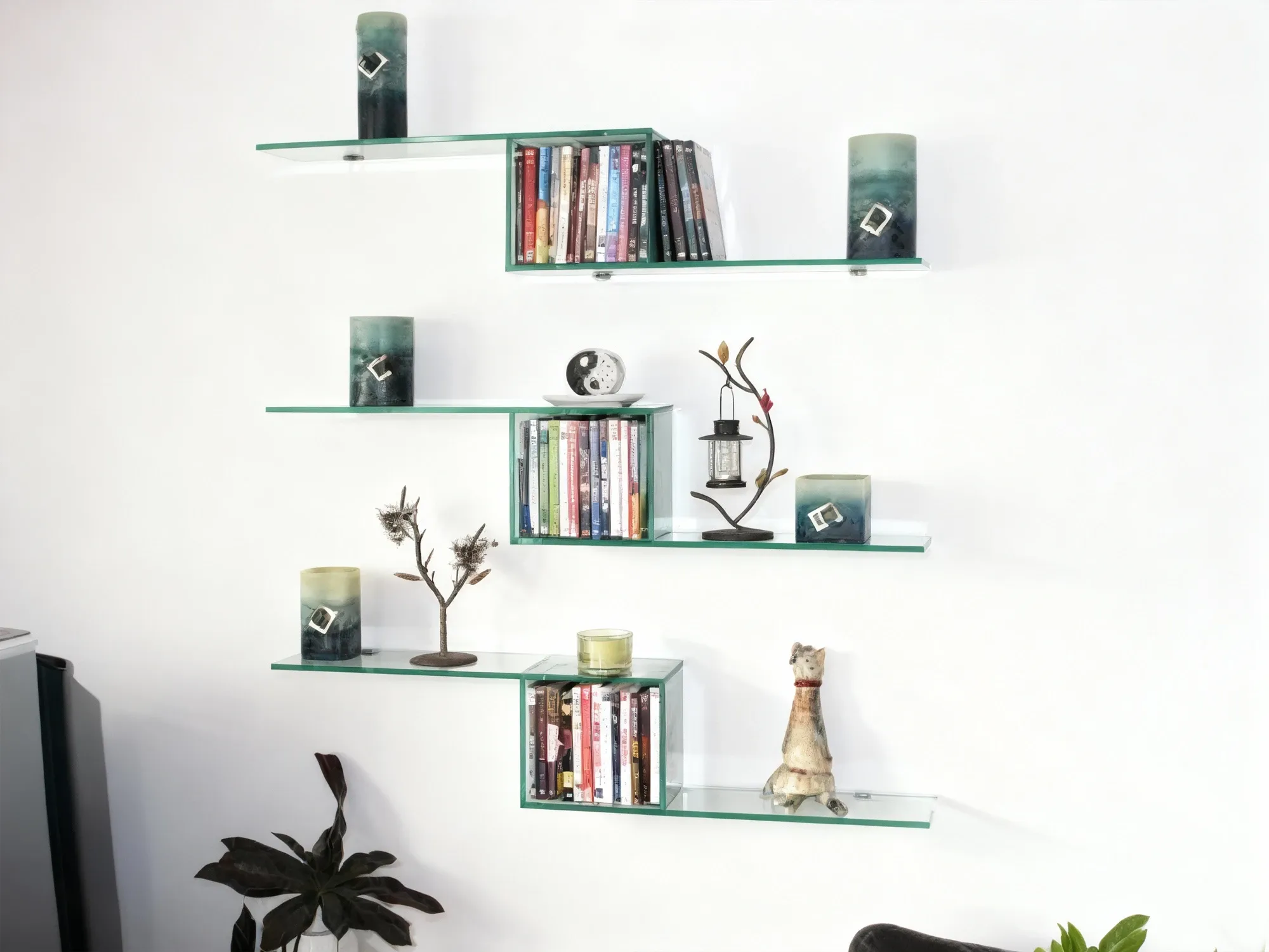 Three unique, S-shaped tempered glass shelves mounted on a white wall, displaying books, decorative candles, and other home decor items.