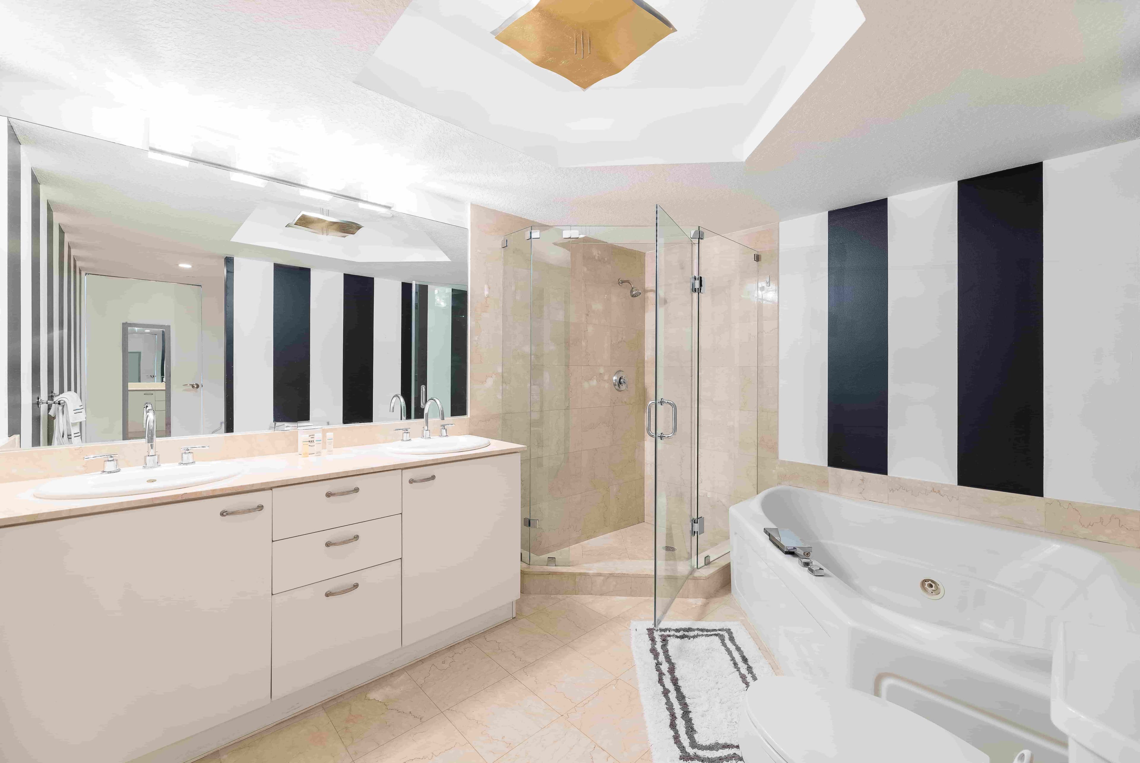 Modern bathroom featuring custom glass shower doors, elegant mirrors with beveled edges, and a luxurious tub, showcasing high-quality tempered glass design.