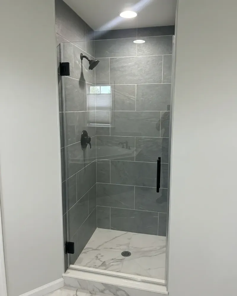 DIY hinged shower door project showing a finished glass shower enclosure