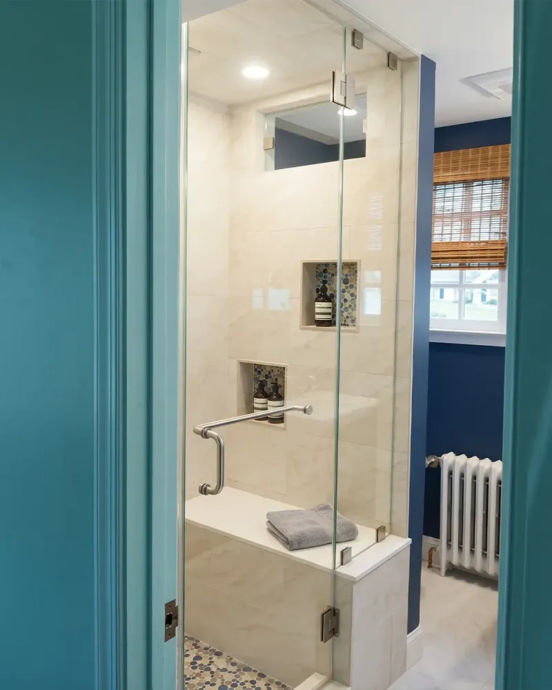 Frameless hinged glass shower door with corner seat and teal accent walls