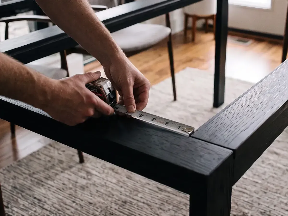 Measuring a table frame with a tape measure