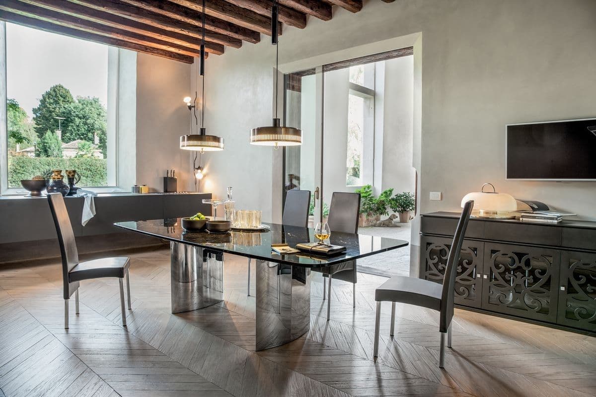 Elegant dining area featuring a custom glass table top with a sleek design, complemented by modern lighting and stylish chairs, showcasing sophisticated interior decor.