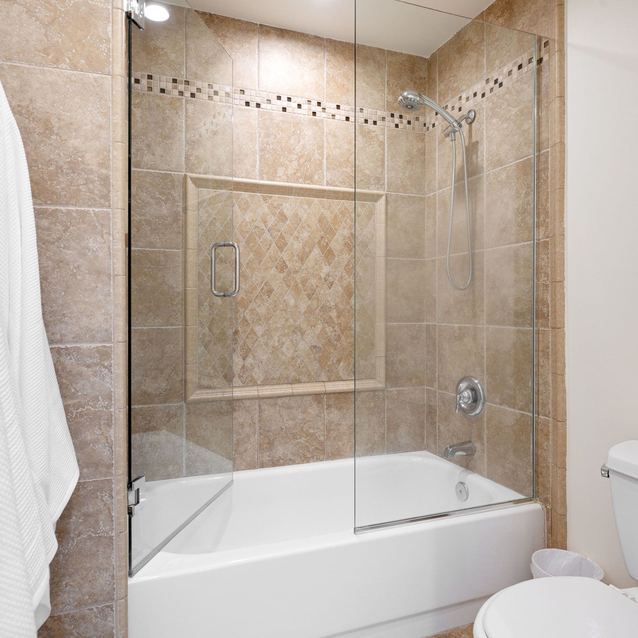 Modern frameless glass shower enclosure with sliding doors, featuring elegant beige tile design and built-in accent border for a luxurious bathroom style.