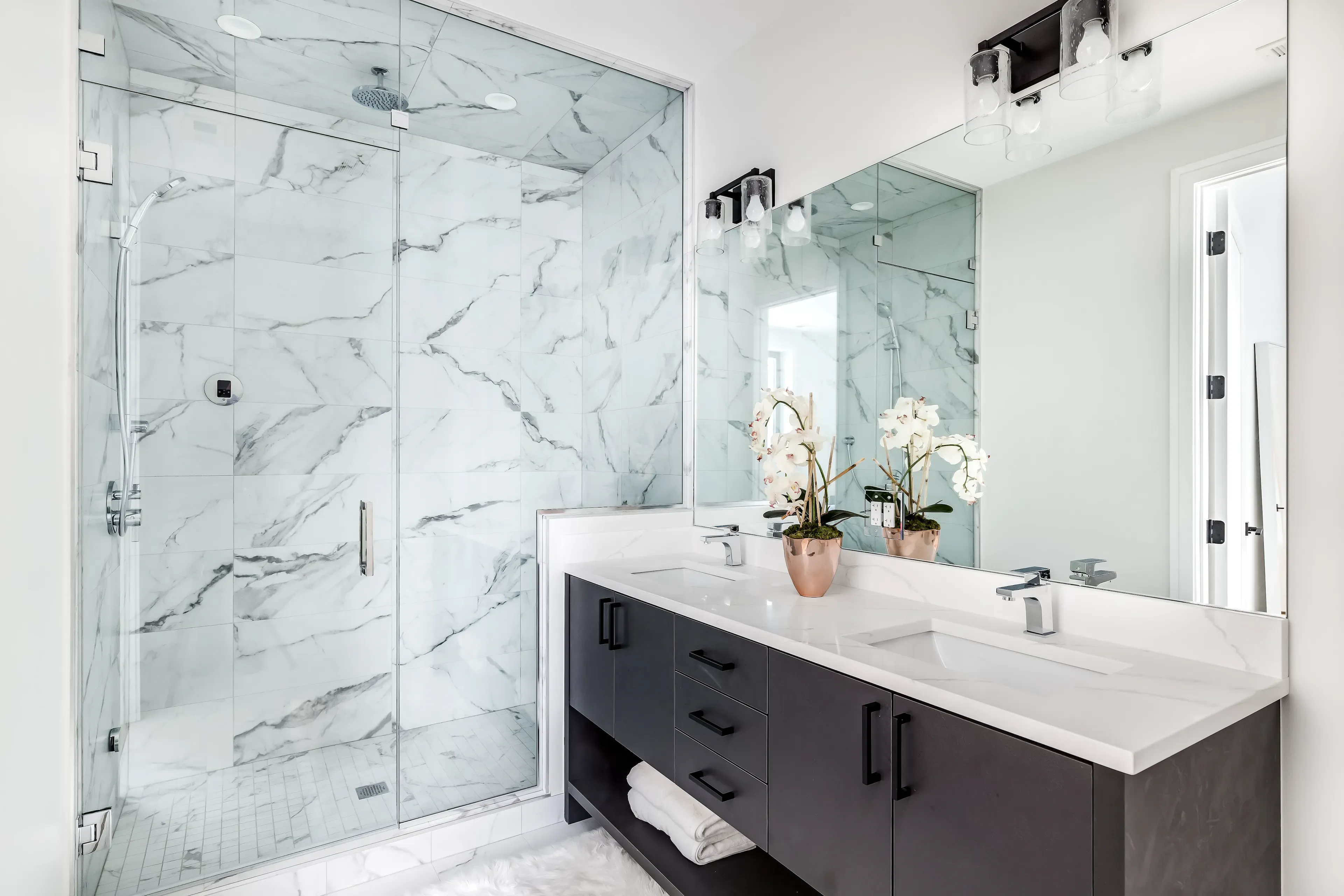 Custom glass shower doors with tempered glass in a modern bathroom featuring a sleek mirror, elegant countertop, and stylish decor, showcasing options for table tops and beveled glass edges.