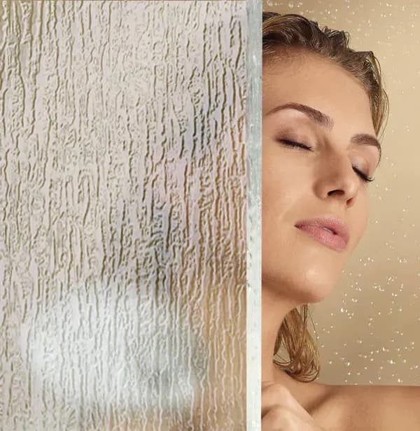 Custom shower doors with textured tempered glass, featuring a woman enjoying a spa-like moment, highlighting the elegance of modern design.