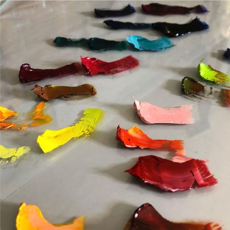 Colorful paint swatches on a smooth glass table top, showcasing a custom glass surface suitable for art and design applications.