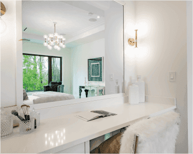 Modern vanity area featuring a large custom mirror, elegant table top, and soft lighting, highlighting the use of tempered glass and beveled glass edge for a sophisticated look in a contemporary setting.