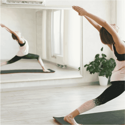 Yoga practice in a bright room featuring a large beveled glass mirror, showcasing custom glass design elements for enhancing spaces like shower doors and table tops.