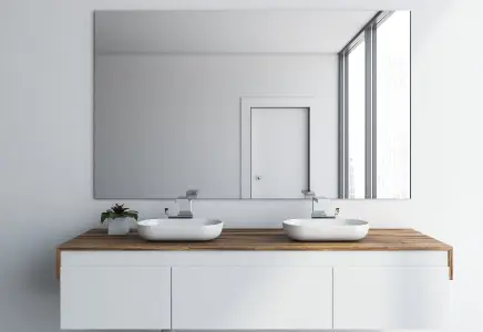 Modern bathroom setup featuring a large custom mirror above a wooden vanity with dual sinks, emphasizing sleek design and quality craftsmanship in custom glass solutions.