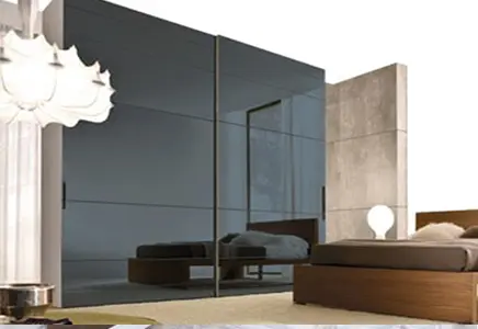 Modern bedroom featuring custom glass sliding wardrobe doors with a sleek, tempered glass finish, complemented by elegant decor.