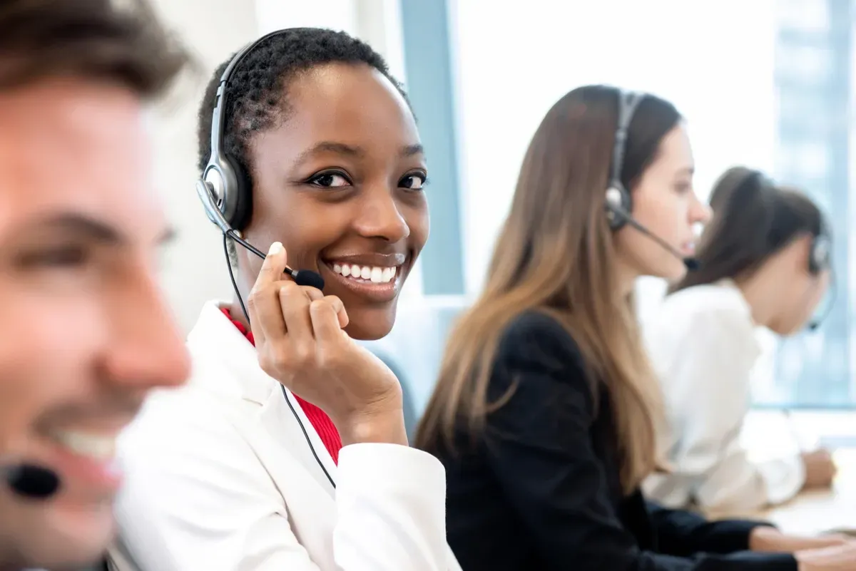 Smiling customer service representative in a headset, providing support for custom glass solutions like shower doors, table tops, mirrors, tempered glass, and beveled glass edges.