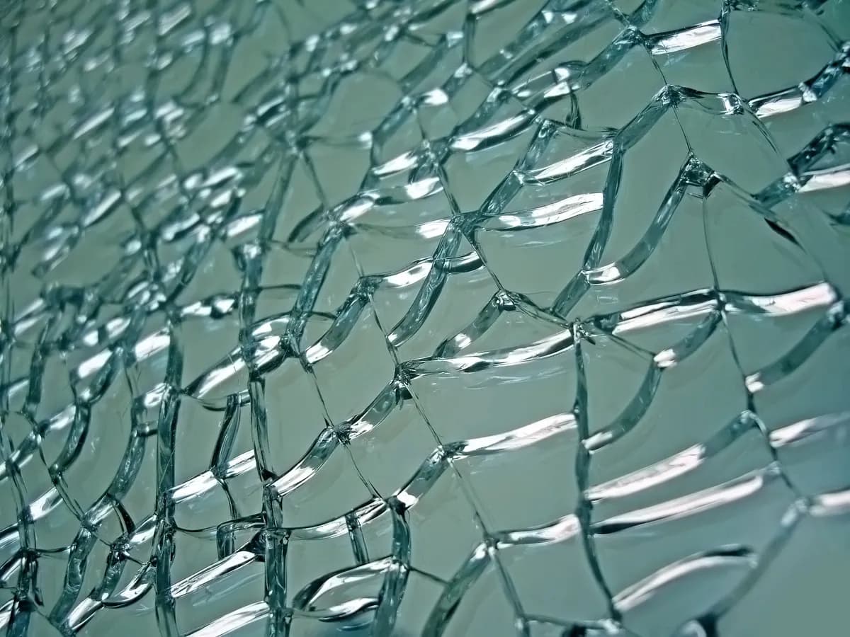 Close-up of fractured tempered glass with a textured surface, ideal for custom glass projects such as shower doors, table tops, and mirrors, showcasing unique beveled glass edges.