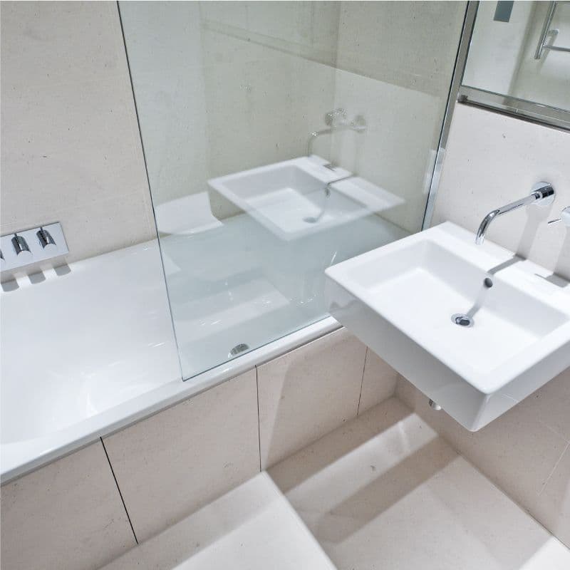 Modern bathroom featuring a glass shower door, sink with a sleek design, and a clean aesthetic complemented by custom glass elements.