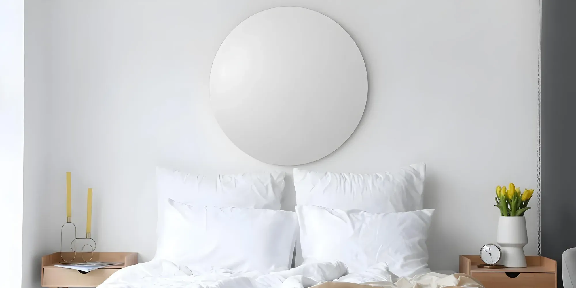 A serene, minimalist bedroom with a large, frameless round mirror mounted on the wall above a bed with crisp white linens.