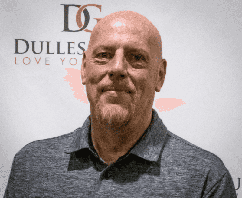 Professional display of custom glass solutions, including shower doors, mirrors, tempered glass, and beveled glass edges, featuring a staff member at Dulles Glass.