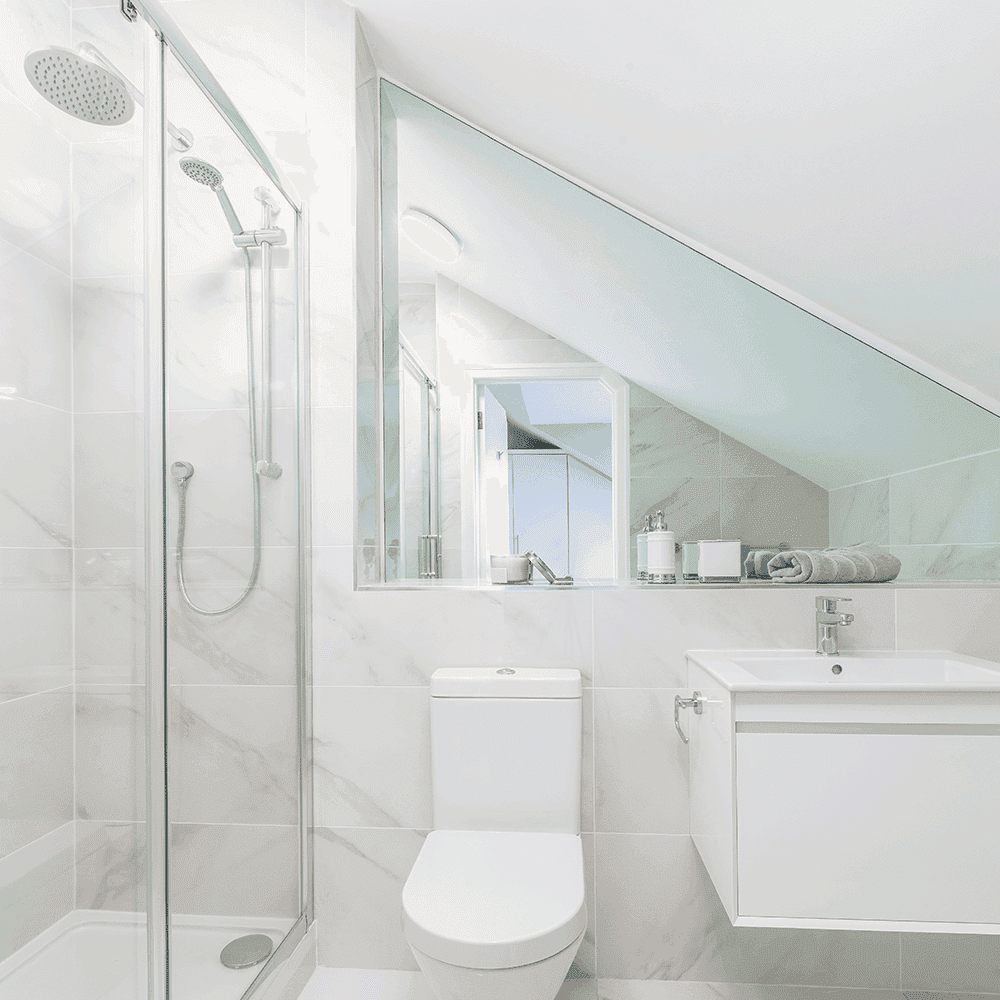 Modern bathroom featuring a glass shower door, sleek mirror, and elegant tile design, showcasing custom glass solutions including tempered and beveled glass edges.