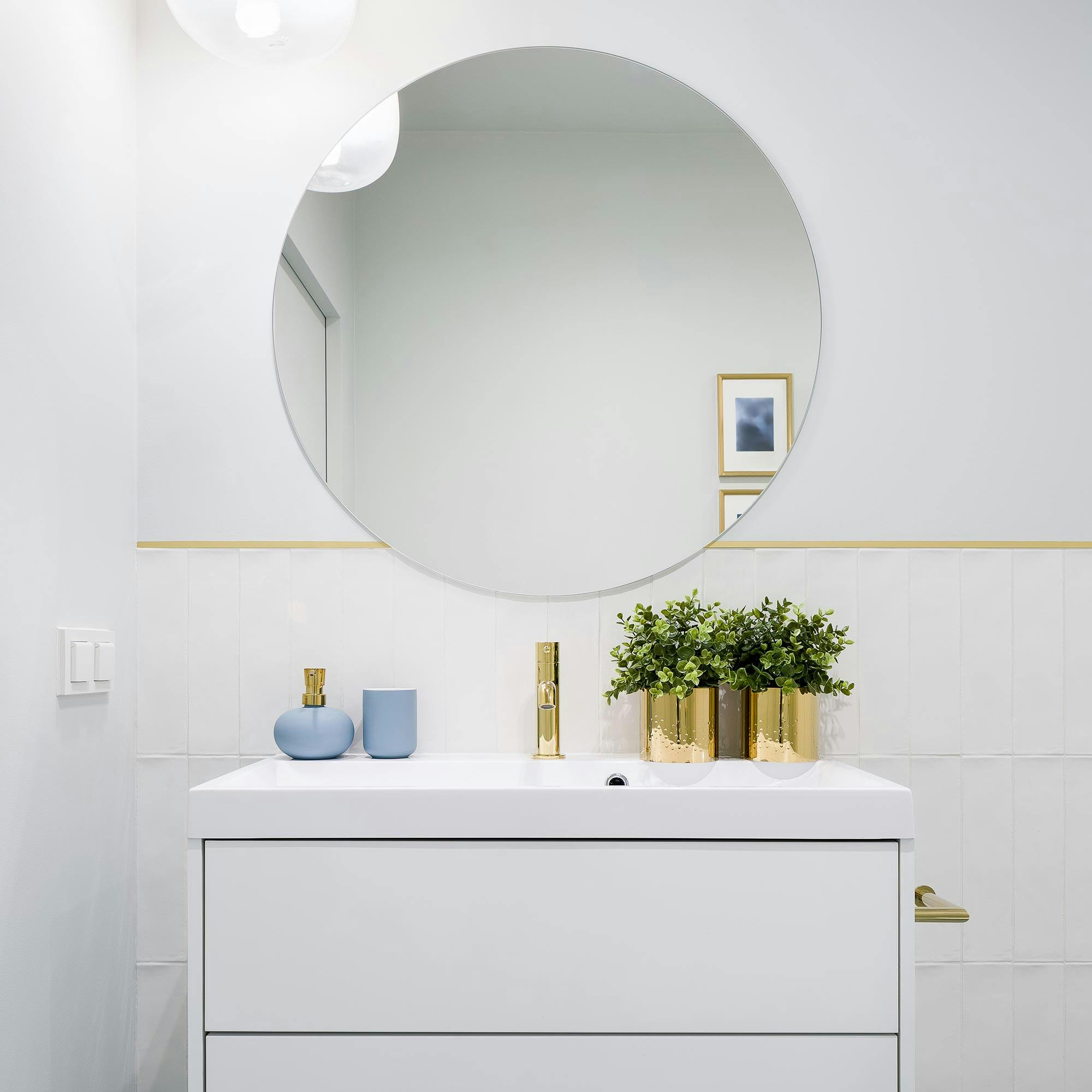 round mirror above white vanity with gold accents
